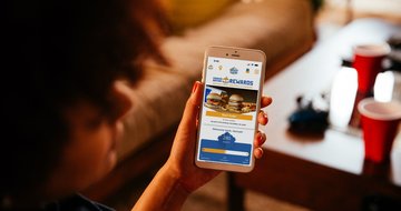 a woman holding a phone with the Craver Nation app on it