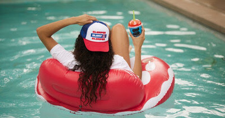 Girl floating on pool float holding a Slurpee drink