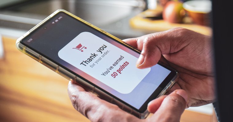 person holds smartphone with rewards savings app shown